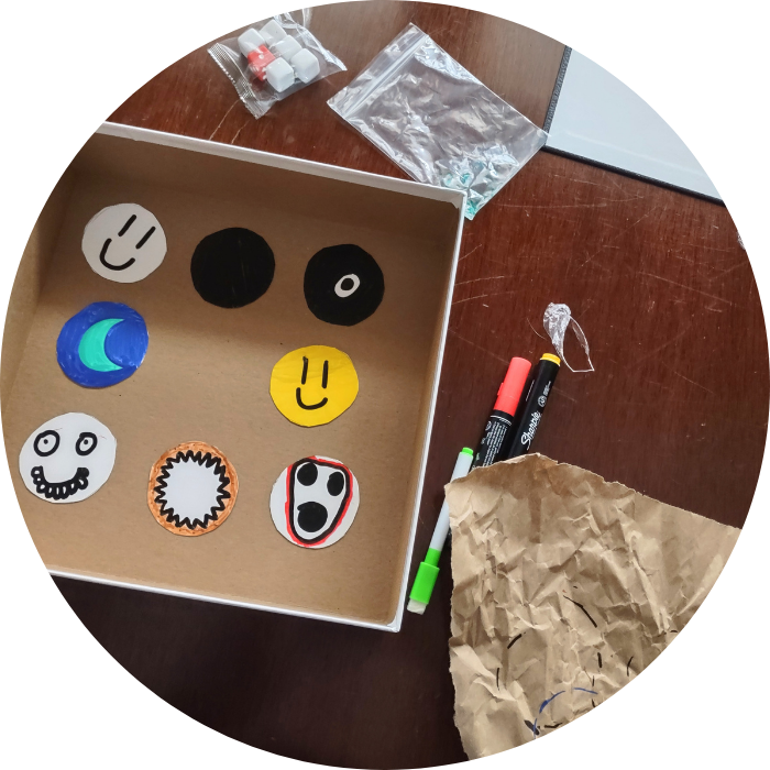 Game supplies including markers and face-shaped cards on a wooden surface.
