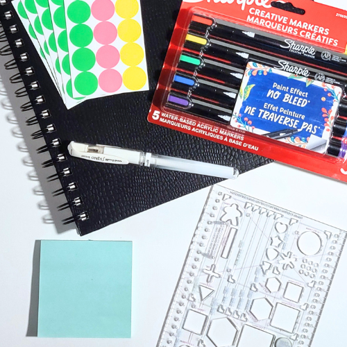 Assorted stationery items including markers, stickers, and a ruler on a white surface.